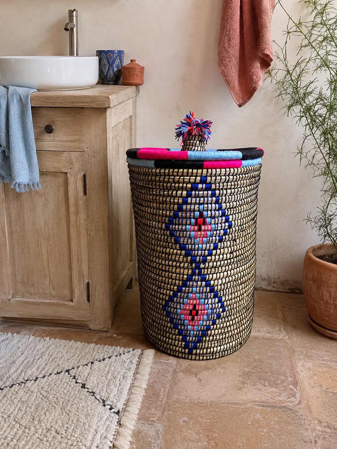 Grand panier à linge artisanal multicolore dans une salle de bain bohème