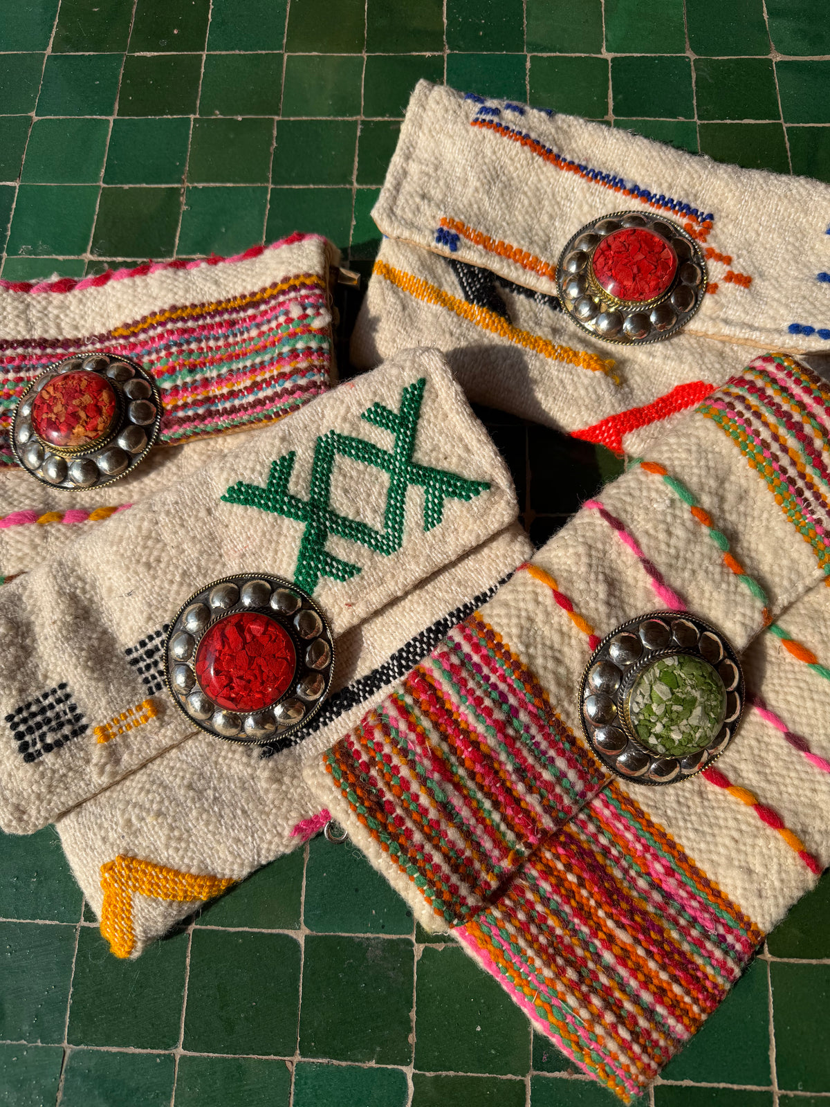Ensemble de quatre pochettes berbères écrues aux motifs colorés et médaillons rouges ou vert