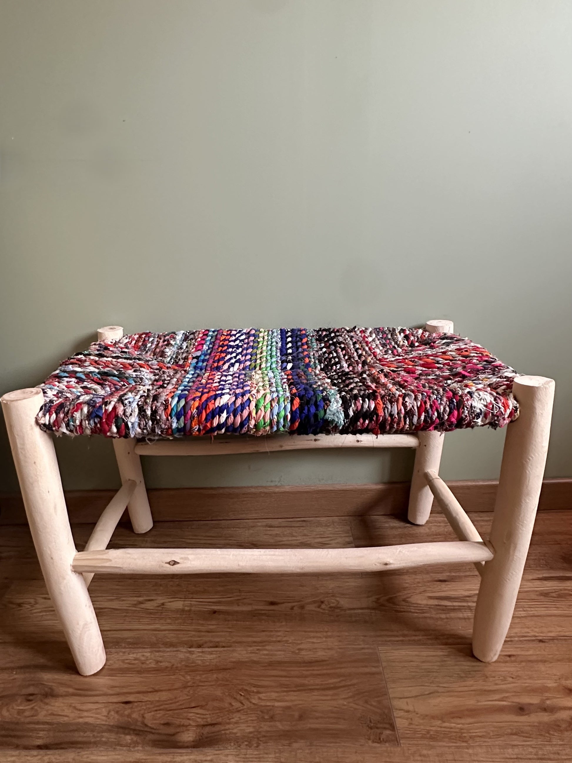 Banc artisanal en bois naturel avec assise tissée en chutes de tissu multicolores aux tons intenses, pièce unique faite main.