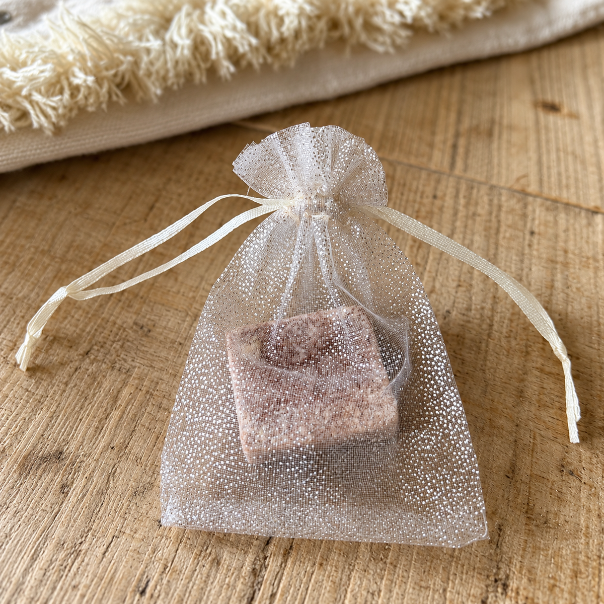 Carré d’ambre solide dans un sachet en organza blanc sur une table en bois