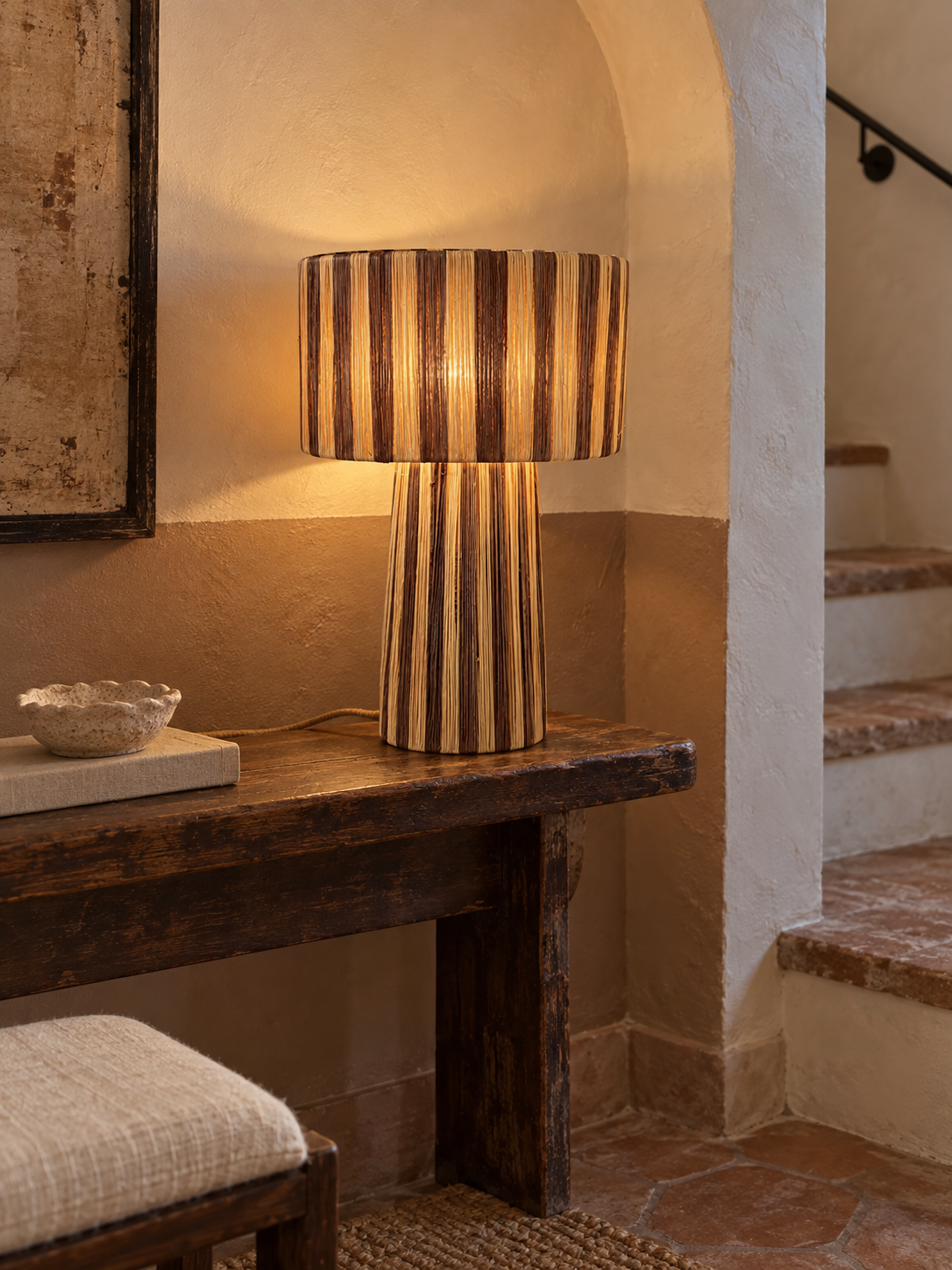 Lampe artisanale en raphia marron et naturel sur un palier bohème