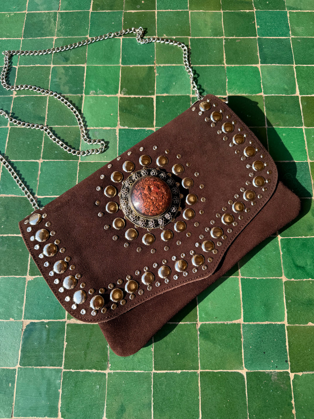 Pochette en daim véritable marron chocolat avec rabat clouté, médaillon central et bandoulière chaîne argentée
