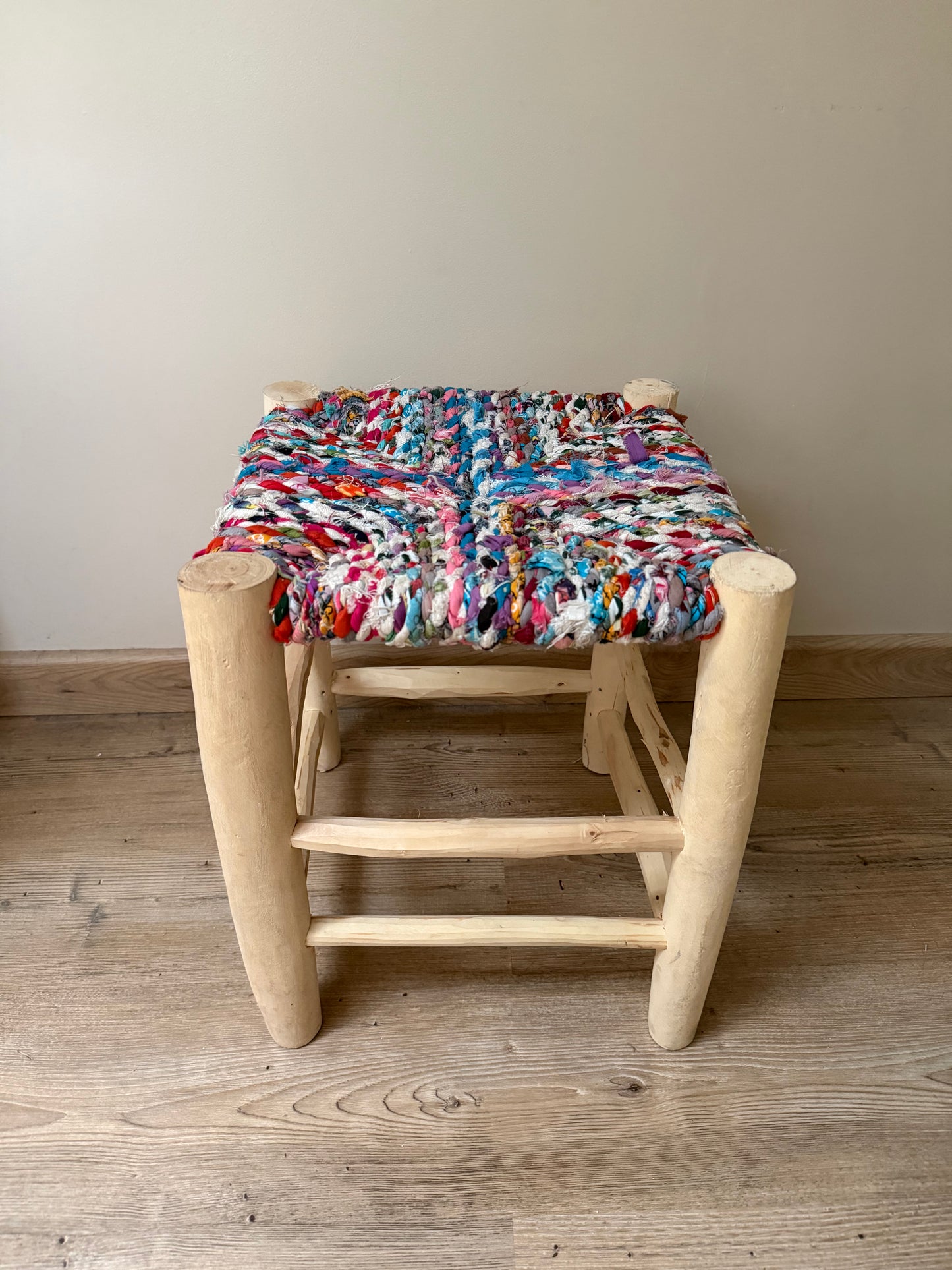Tabouret Boucherouite fait main aux nuances rose, bleu et blanc avec pieds en bois naturel