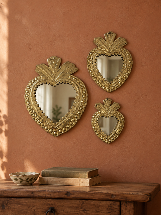 Trois miroirs cœur ex-voto artisanaux en cuivre sur un mur terracotta