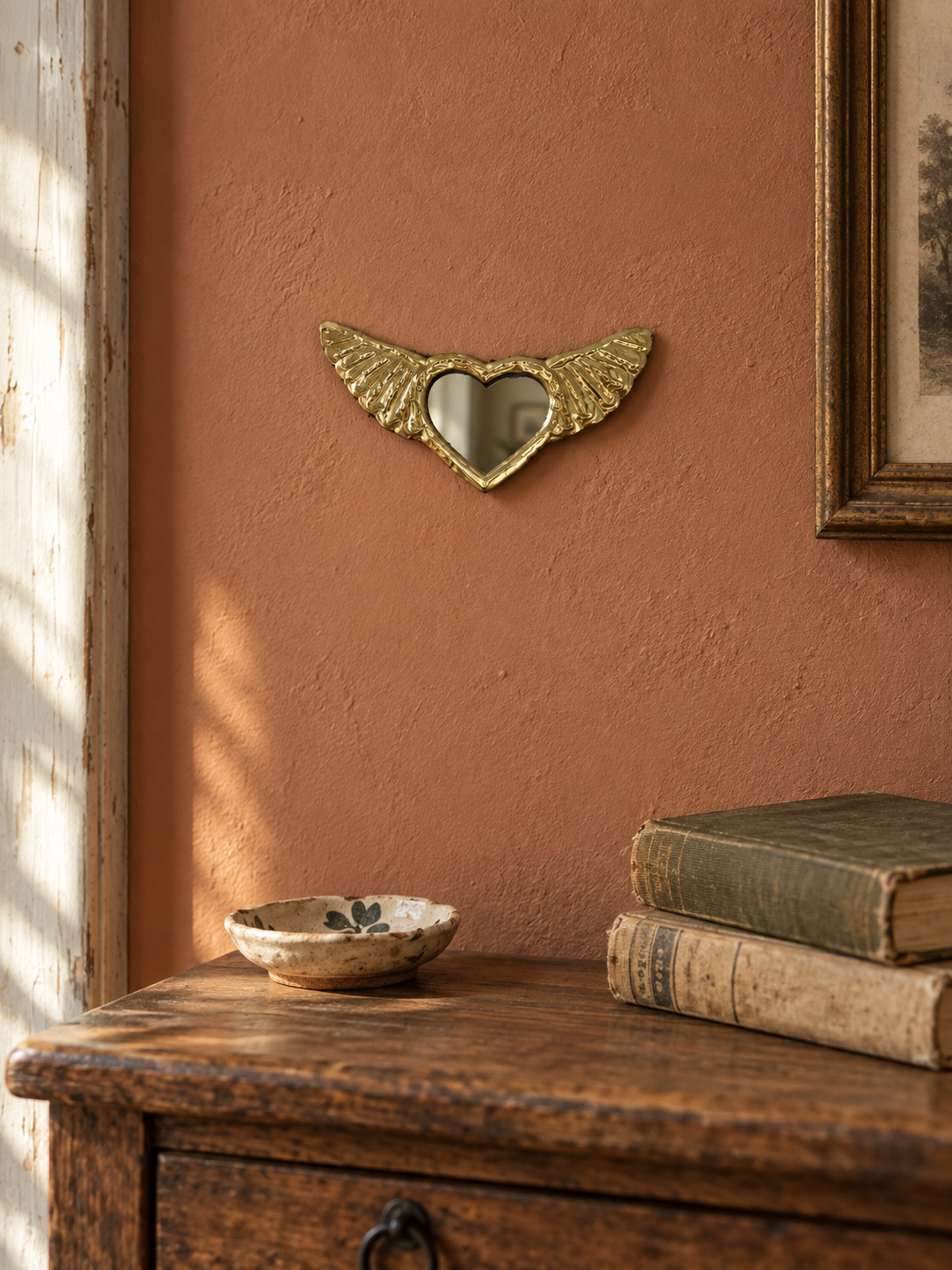 ex-voto cœur ailé en cuivre installé sur un mur terracotta dans une décoration chaleureuse
