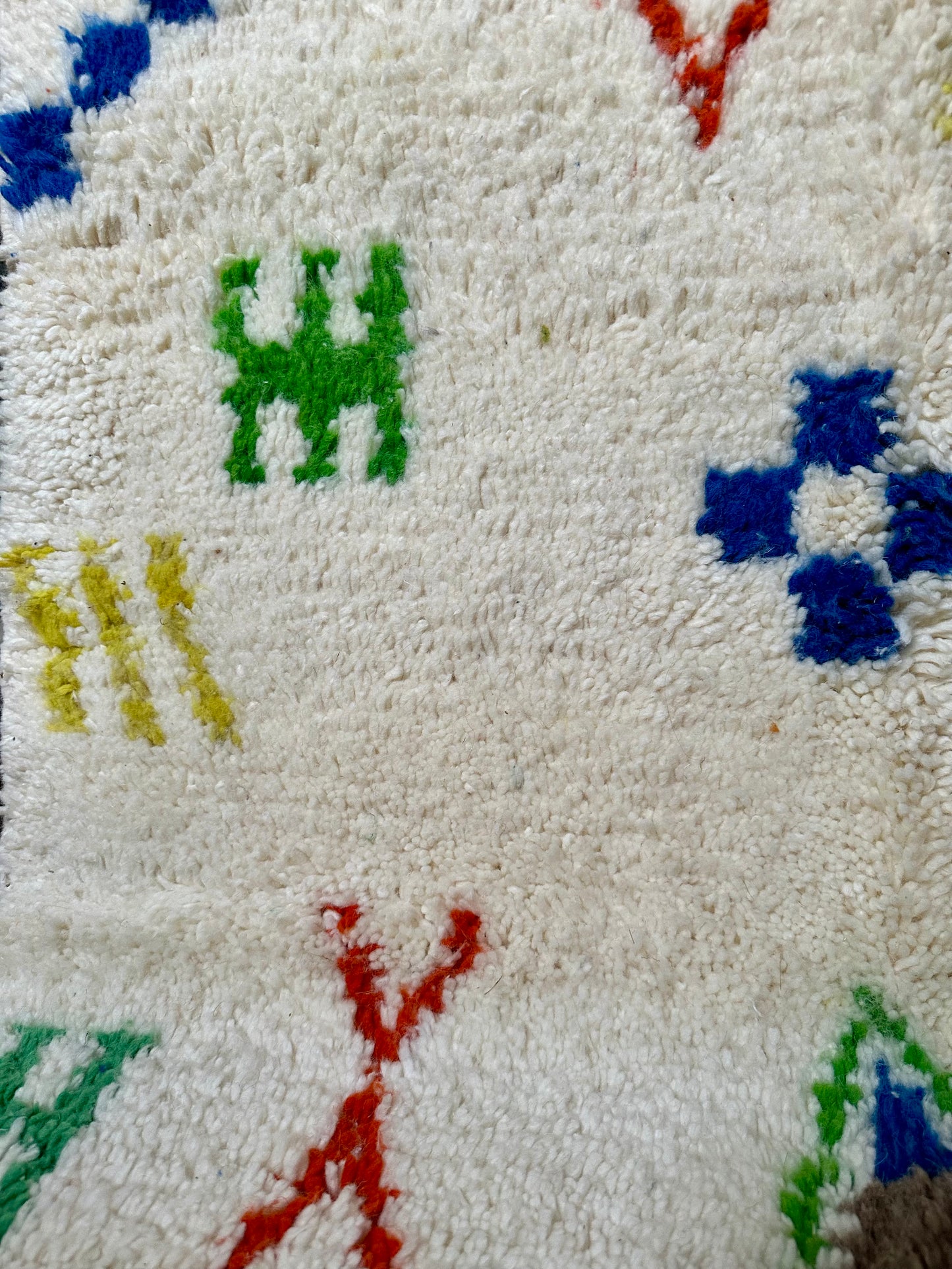 Détail des motifs colorés d’un tapis berbère marocain en laine, tissé à la main par des artisans selon un savoir-faire traditionnel.