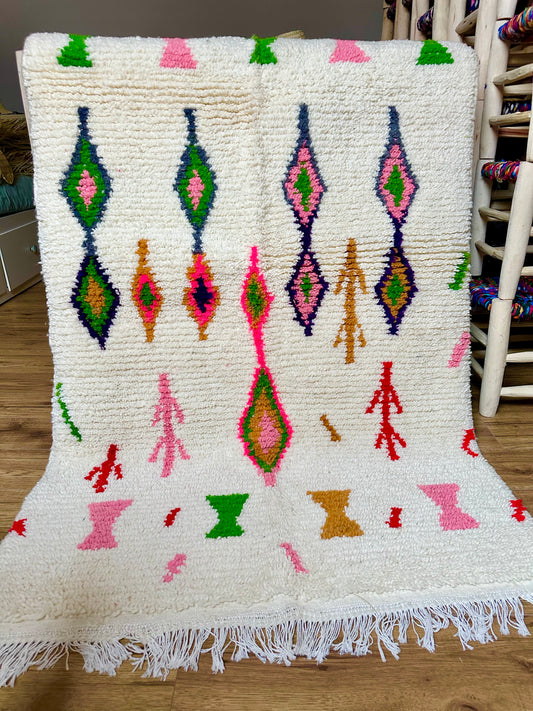 Tapis berbère marocain en laine 100 % naturelle, fait main au Maroc, pièce artisanale unique aux motifs colorés et franges traditionnelles.