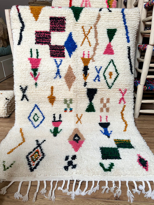 Tapis berbère marocain en laine 100 % naturelle, fait main au Maroc, pièce artisanale unique aux motifs géométriques colorés et franges traditionnelles.